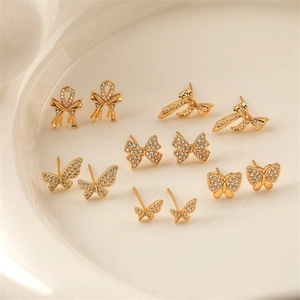 Close-up of gold plated bow and butterfly earrings with diamonds on a ceramic plate