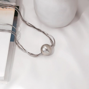 Detailed view of silver minimalist necklace with three-strand snake chains and a textured ball pendant