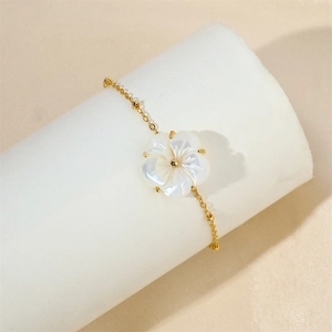 Detail of 18k gold plated shell flower bracelet with white pearl on display stand