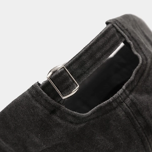 Detail of adjustable silver metal buckle and washed cotton texture on dark grey baseball cap