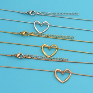 Detailed view of heart pendants on snake chains in silver, gold, and rose gold finishes