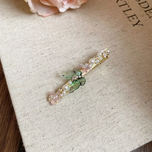 Détail de la pince à cheveux florale avec papillons en cristal et perles sur fond rétro