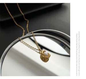 Detailed view of irregular gold hammered pendant with moonstone and fine cross chain