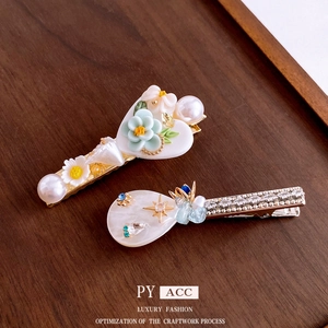 Elegant floral hair clips with pearls and rhinestones on dark walnut wood tray