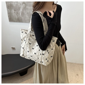 Detailed texture of white corduroy tote bag with black bow patterns and soft fabric