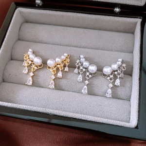 Detail showing gold and silver pearl drop earrings with sparkling cubic zirconia in a box
