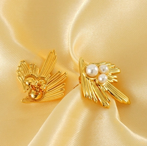 Detailed macro view of vintage 18K gold swallow pearl earrings on satin fabric