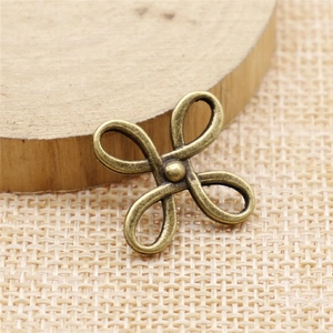 Detail of clover-shaped bronze alloy connector for DIY jewelry on textured fabric