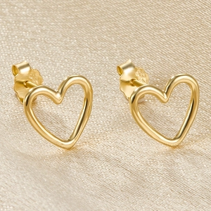 Macro view of gold hollow heart-shaped S925 sterling silver stud earrings on fabric
