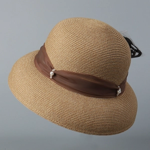 Dettaglio di un elegante cappello di paglia con nastro marrone scuro e perle bianche