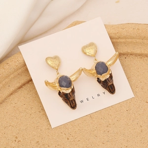 Macro shot of vintage bull head earrings with golden heart studs and grey gemstone detail