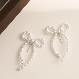Detail shot of elegant bow-shaped pearl earrings with smooth metallic silver studs