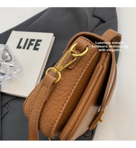 Close-up of brown litchi grain leather bag with premium gold metal hook and hardware