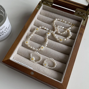 Detailed view of French-style freshwater pearl necklace and daisy rings in a jewelry box