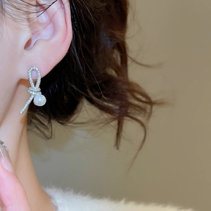 Side view of model wearing silver knotted zircon earring with a round white pearl detail