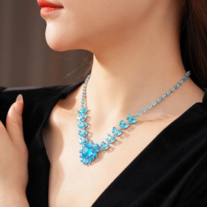 Close-up of a silver necklace with sparkling blue zircon heart-shaped pendant on a model