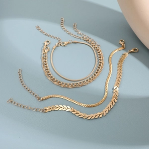 Detail showing four gold-layered chains including snake, flat, and arrow link bracelets