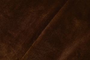 Macro view of luxurious deep brown velvet fabric with smooth silk-like texture and soft sheen