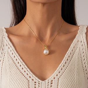 Detail of elegant gold necklace featuring a round pearl pendant with rhinestone accents