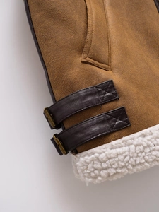 Detail of brown faux suede vest with dark leather strap and white fleece lining