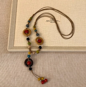 Detailaufnahme der Boho-Halskette mit Holzringen und bunten Perlen auf Leinen