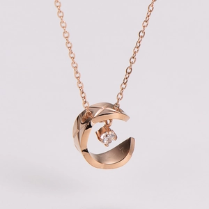 Macro shot of rose gold C-shaped pendant with quilted pattern and sparkling zircon stone