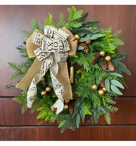 Beautiful rustic Christmas wreath with pine cones and golden bells on a dark wooden door