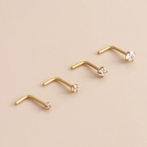 Close-up of four gold stainless steel L-shaped nose studs with clear cubic zirconia stones