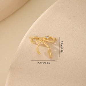 Macro view of gold bow pendant with zircon stones and dimensions 2.2cm x 1.9cm