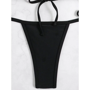 Minimalist black lace-up bikini bottom on white marble background, flat lay perspective