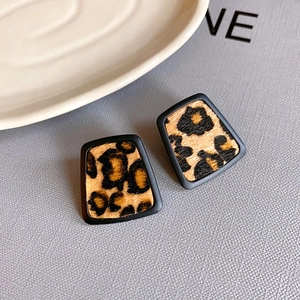 Vue macro des boucles d'oreilles trapèze vintage avec imprimé léopard et monture noire mate