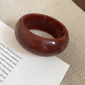 Macro shot of wide marble-patterned resin bangle in amber brown and white tones