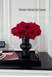 Close-up of red velvet artificial roses in a black glossy ceramic vase for table decor