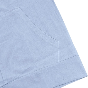Detail shot of light blue linen shirt showing double-needle stitching and side pocket texture