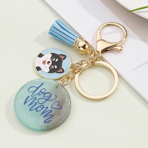 Detailed view of a dog mom keychain with blue tassel and shiba inu charm on green background