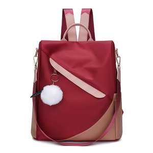 Detail of burgundy waterproof nylon backpack with plush charm and anti-theft zipper design