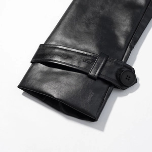 Detail of black leather coat cuff with button and strap on a minimalist white background