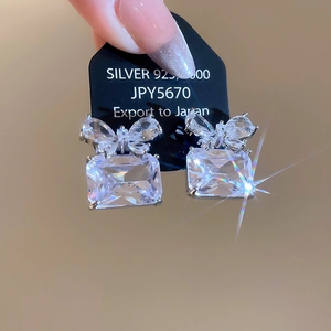 Macro shot of 925 silver stud earrings with square zircon and bowknot detail