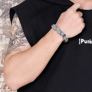 Detail of a chunky silver stainless steel woven chain bracelet for men with punk tattoos