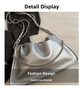 Close-up of silver textured cloud bag with a chunky metal chain strap on a neutral surface