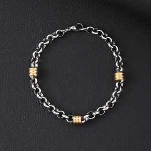 Detail of silver titanium steel curb chain with gold textured beads on black leather