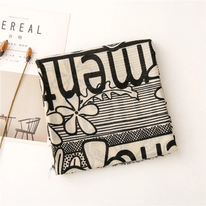 Flat lay detail of printed cotton linen scarf with black letters and floral patterns