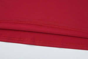 Détail de l'ourlet d'une robe en tricot rouge montrant la couture et la texture