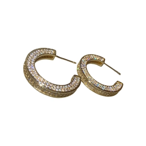 Sparkling C-shaped gold-plated earrings with pave-set cubic zirconia on white background