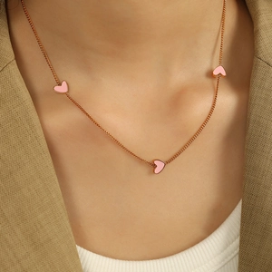 Rose gold necklace with pink heart pendants shown worn on neck for a sweet modern style