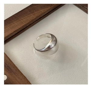 Polished silver ring with rounded droplet design shown on a glass surface with wooden frame