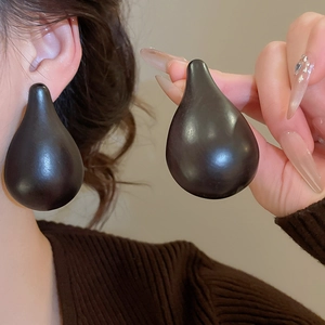 Detail of elegant black teardrop earrings on model with high gloss finish and retro style