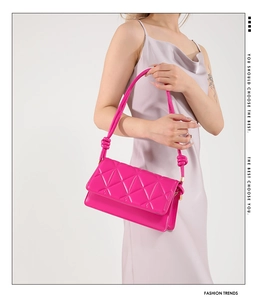 Detailed view of magenta quilted leather handbag with knot shoulder strap detail