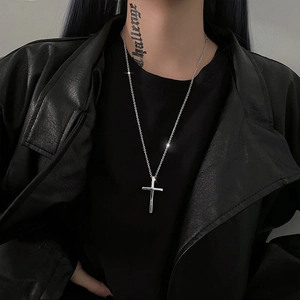 Close-up of a silver cross pendant necklace worn over a black leather jacket