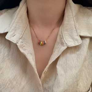 Macro view of a colorful enamel ring pendant necklace on a gold chain worn by a model